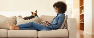 A young woman relaxes on the sofa with her digital tablet at home.
