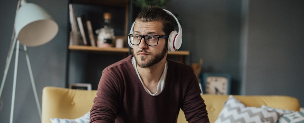 Stylish man using a laptop to listen to a podcast